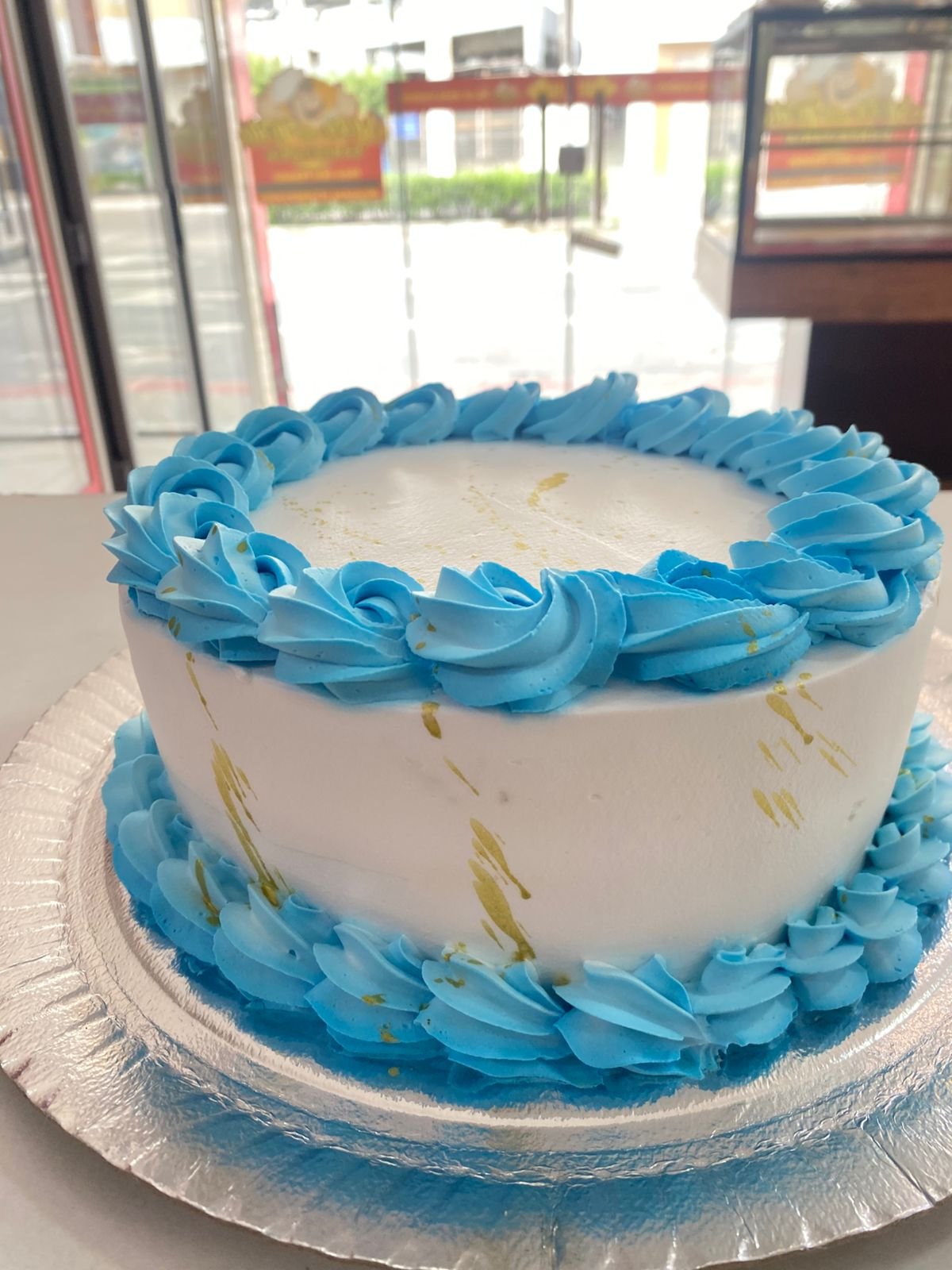 Bolo branco com chantilly azul e respingos dourados