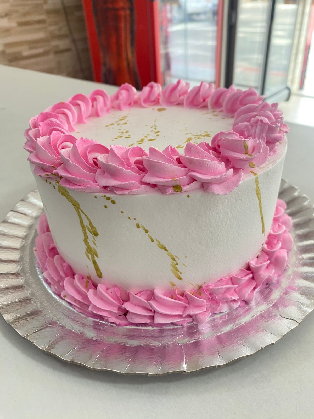 Bolo branco com chantilly rosa e respingos dourados